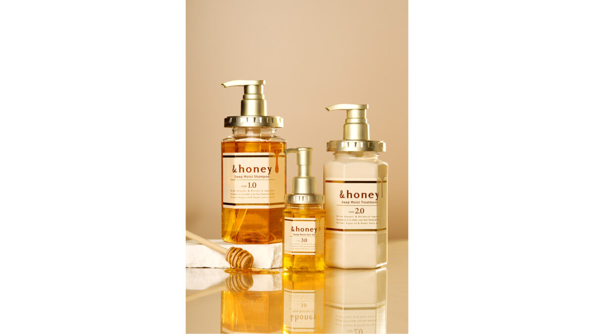 Three &honey haircare bottles—Deep Moist Shampoo, Treatment, and Hair Oil—displayed with a honey dipper.