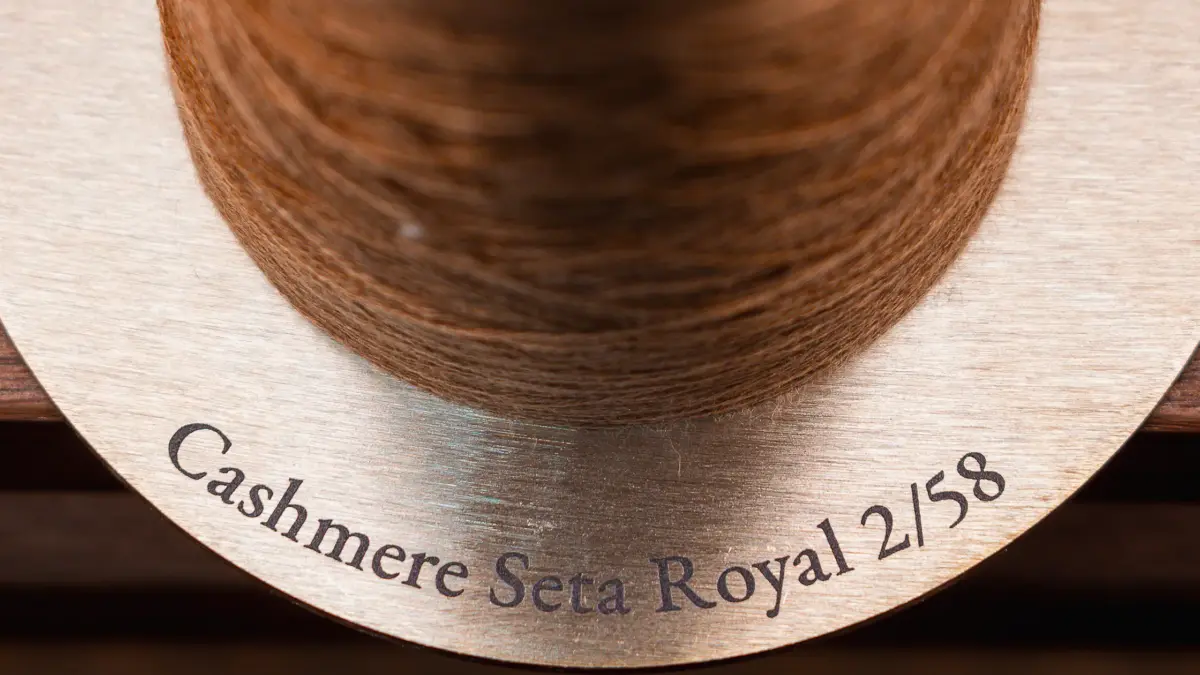 Close-up of a spool of brown yarn labeled Cashmere Seta Royal 2/58.