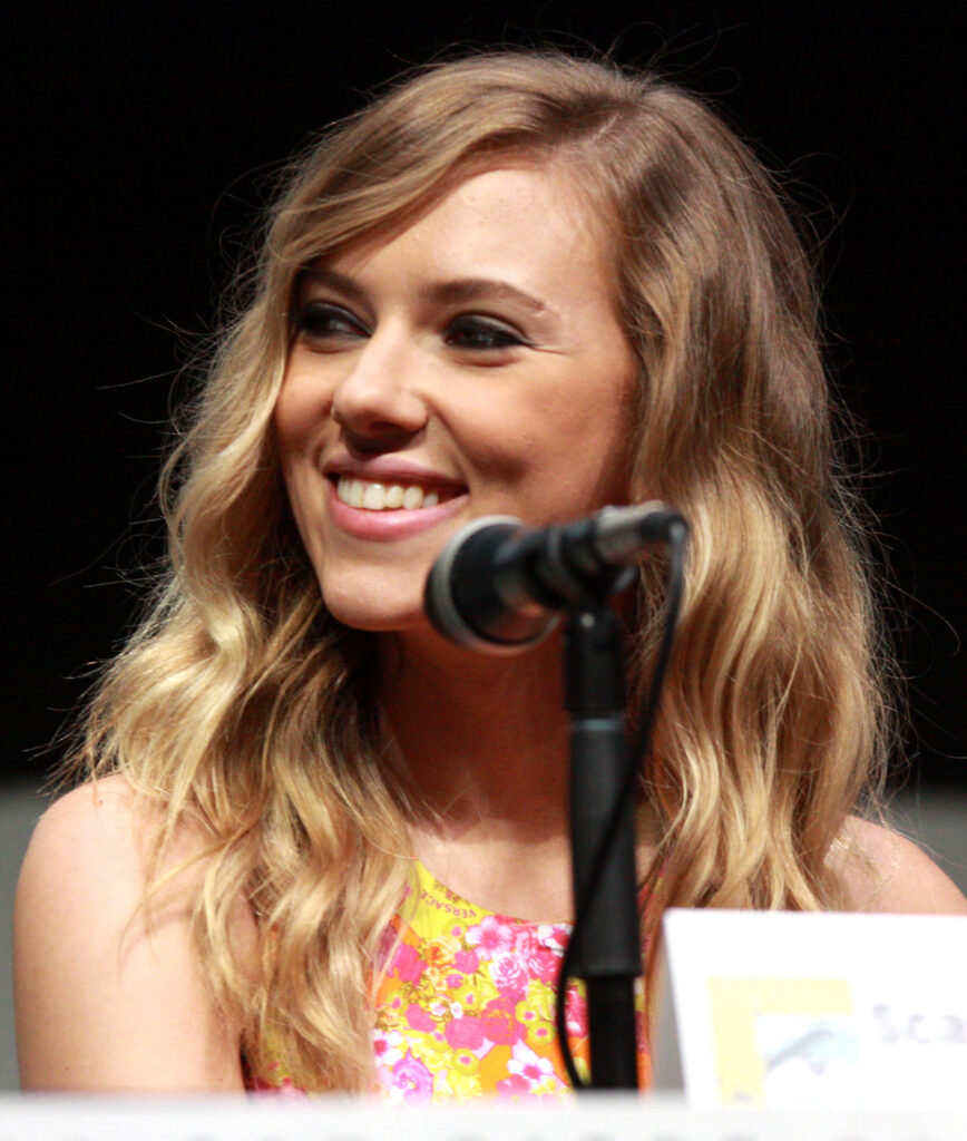 Scarlett Johansson smiling behind a microphone at a 2013 convention panel.