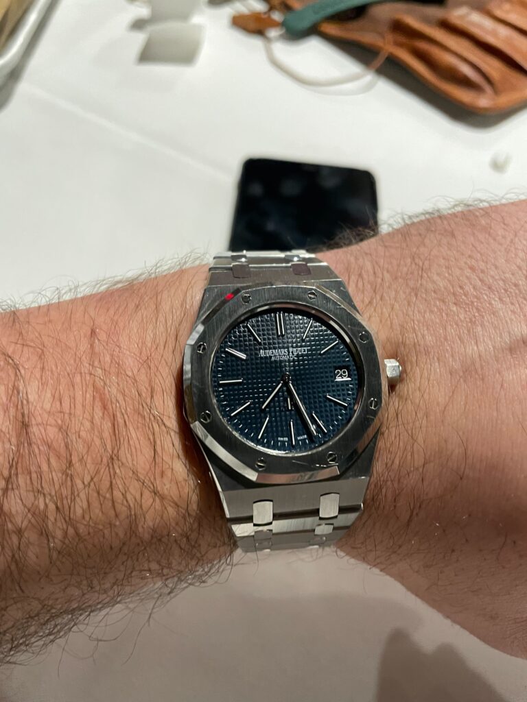 An Audemars Piguet Royal Oak watch with a blue dial worn on a hairy wrist.