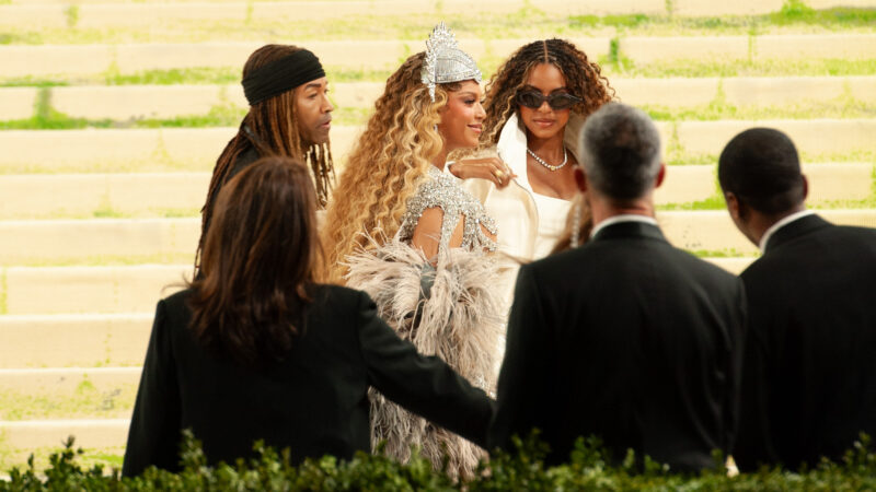 Beyoncé, Blue Ivy Carter, and others stand on steps at the Met Gala surrounded by security.