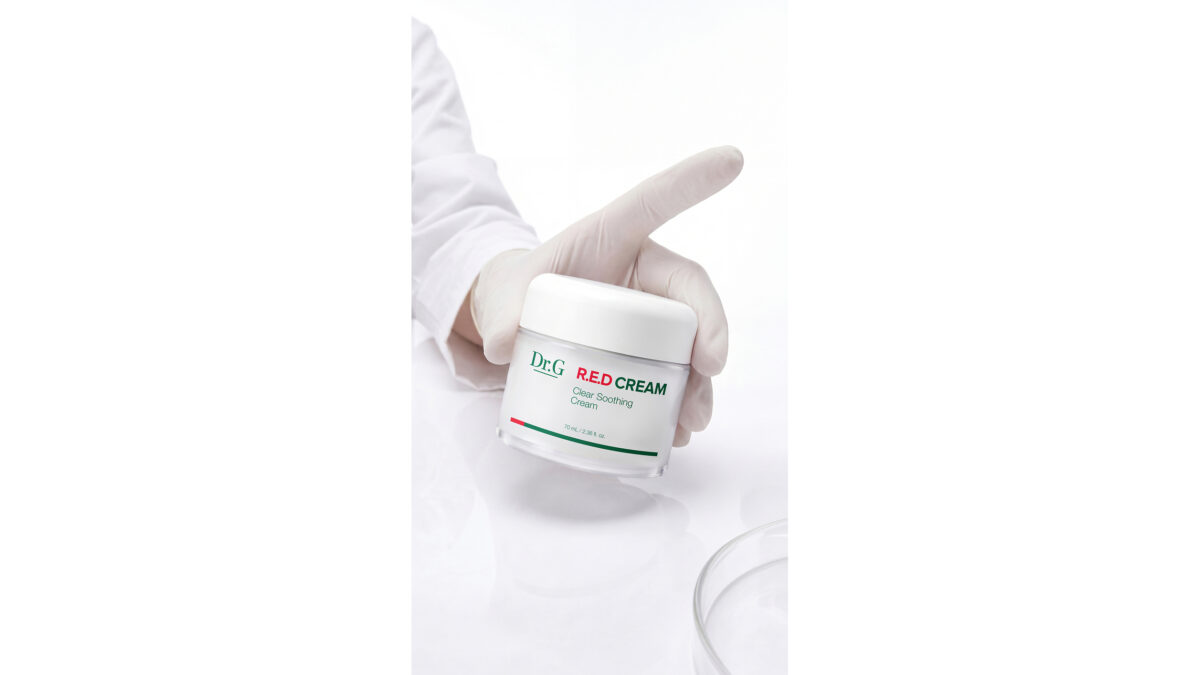 A gloved hand holds a jar of Dr.G R.E.D Cream against a white background.