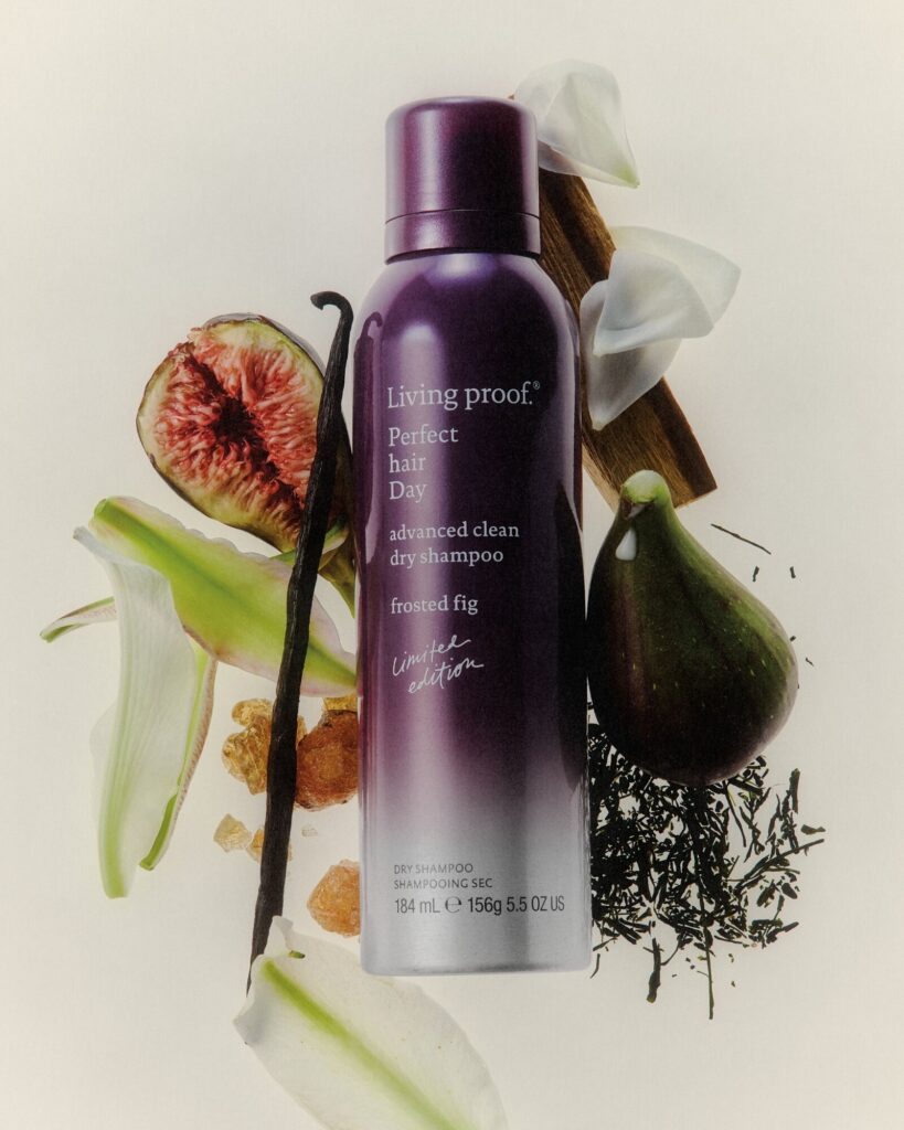 A can of Living Proof Perfect Hair Day Frosted Fig dry shampoo surrounded by figs, flowers, and vanilla pods.