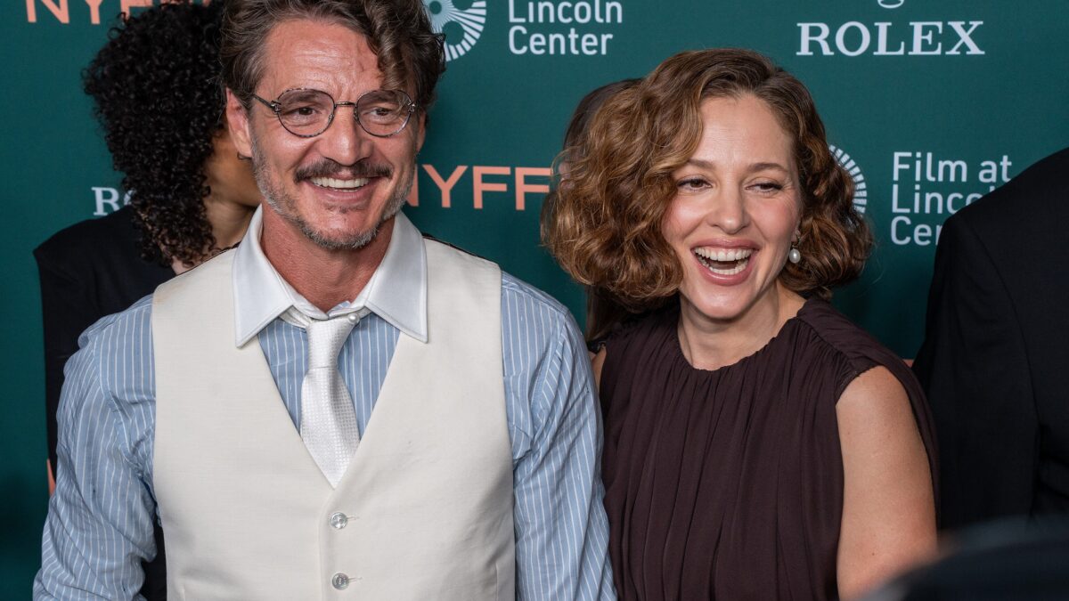 A man in a vest and tie and a woman in a dark dress smile together at a film festival step-and-repeat with NYFF and Rolex logos.
